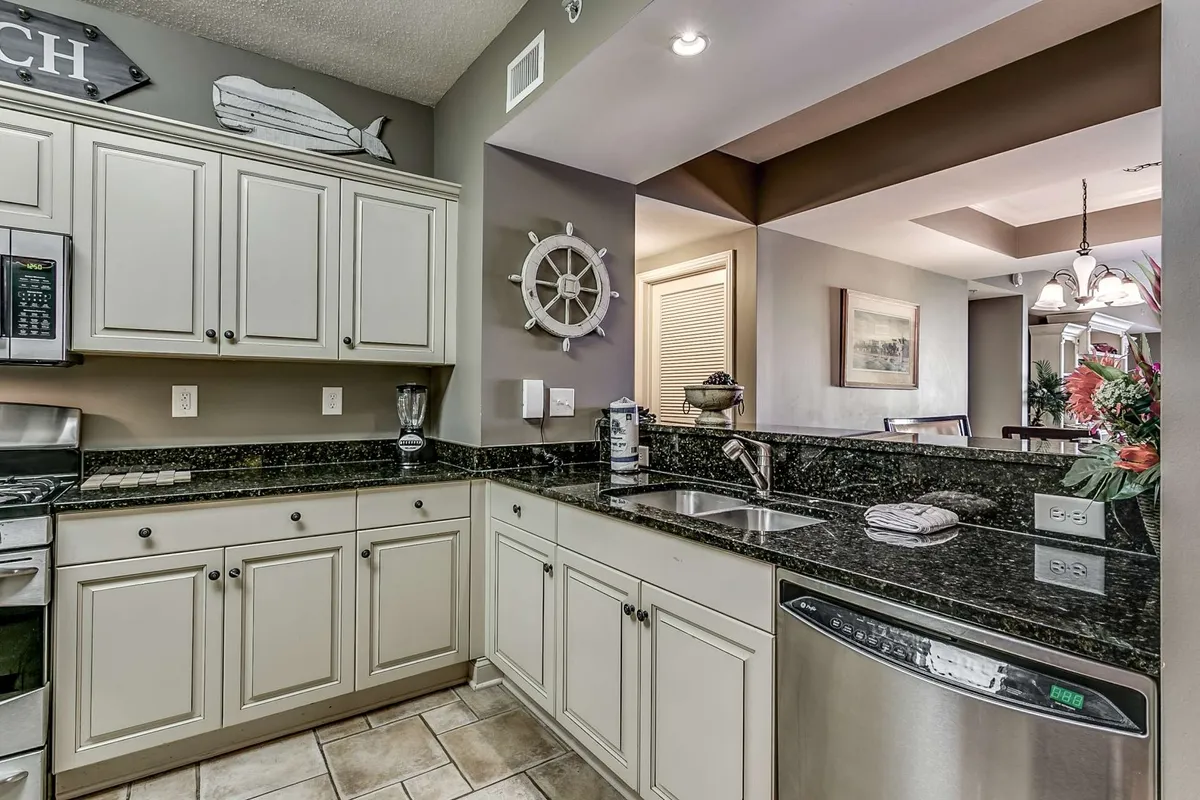 A spacious kitchen area with granite countertops, stainless steel appliances, and nautical decor. The layout allows for easy meal preparation and group gatherings, while the decor reinforces a coastal ambiance.