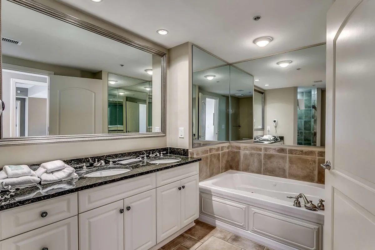 This tranquil bathroom features dual sinks, a large mirror, and a bathtub, evoking a spa-like atmosphere ideal for relaxing after a long day or preparing for special occasions.